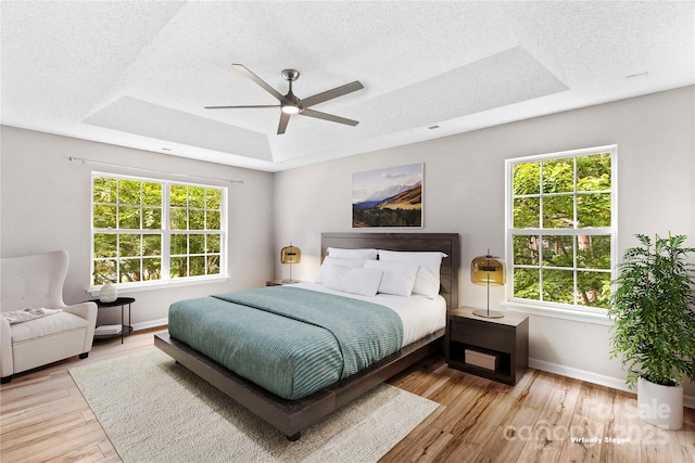 145 Summerbrook Ln, Mooresville, NC 28117 - bedroom with multiple windows, a tray ceiling, wood finished floors, a textured ceiling, and ceiling fan