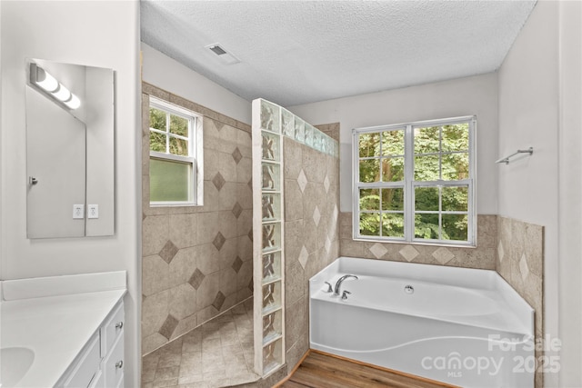 145 Summerbrook Ln, Mooresville, NC 28117 - full bathroom with vanity, a garden tub, a walk in shower, wood finished floors, and a textured ceiling