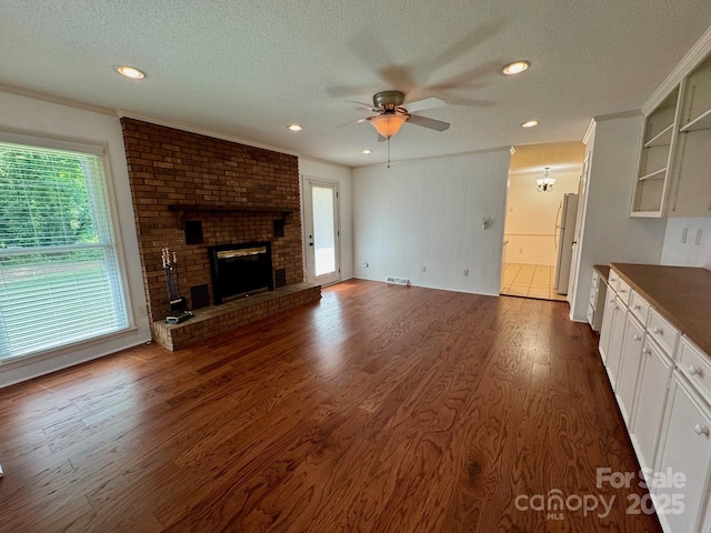 635 Windsor Pl NE, Concord, NC 28025 - unfurnished living room featuring healthy amount of natural light, a textured ceiling, a ceiling fan, dark wood-style flooring, and recessed lighting