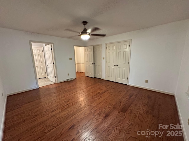 635 Windsor Pl NE, Concord, NC 28025 - unfurnished bedroom with wood finished floors, two closets, and a ceiling fan