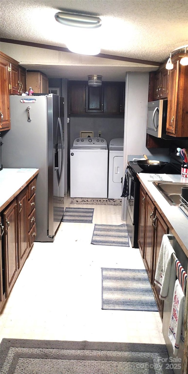 101 Branch Breeze Ln, Zirconia, NC 28790 - kitchen featuring washing machine and clothes dryer, appliances with stainless steel finishes, a textured ceiling, light countertops, and light flooring