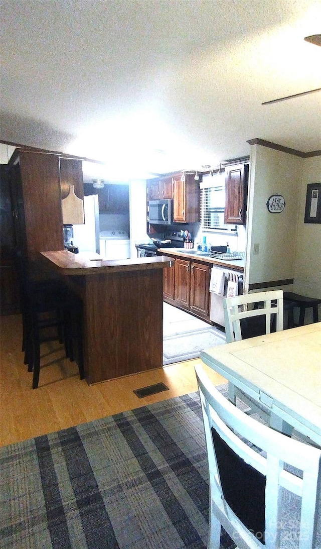 101 Branch Breeze Ln, Zirconia, NC 28790 - kitchen featuring dishwashing machine, stainless steel microwave, light wood-type flooring, and a peninsula