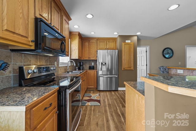 1974 Redwood Dr, Oakboro, NC 28129 - kitchen with stainless steel appliances, wood finished floors, brown cabinetry, recessed lighting, and backsplash