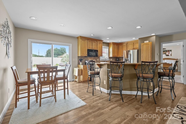 1974 Redwood Dr, Oakboro, NC 28129 - kitchen with stainless steel fridge with ice dispenser, black microwave, light wood finished floors, plenty of natural light, and recessed lighting