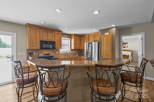 1974 Redwood Dr, Oakboro, NC 28129 - kitchen featuring stainless steel appliances, light wood-type flooring, decorative backsplash, a breakfast bar area, and recessed lighting