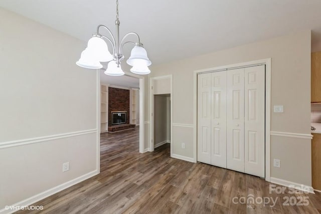 608 Laurel Fork Dr, Matthews, NC 28105 - unfurnished dining area with a chandelier, wood finished floors, a brick fireplace, and built in features