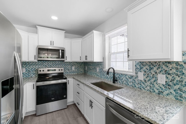 801 Evening Shade Ln, Gastonia, NC 28052 - kitchen with stainless steel appliances, backsplash, white cabinets, light wood-style floors, and light stone counters
