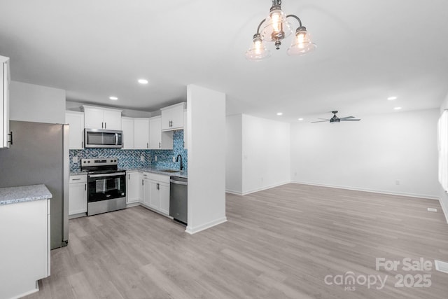 803 Evening Shade Ln, Gastonia, NC 28052 - kitchen with stainless steel appliances, light wood finished floors, a ceiling fan, backsplash, and open floor plan
