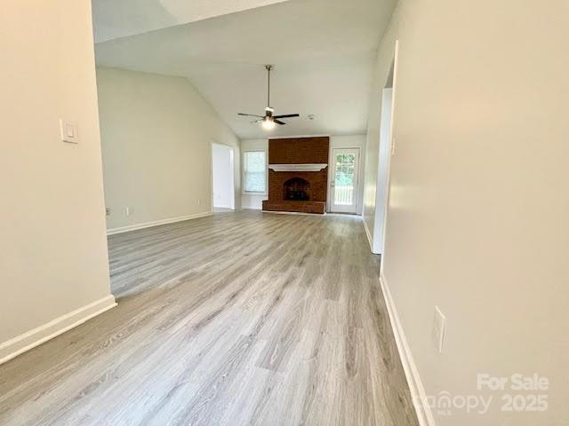 205 Hidden Spring Dr, Salisbury, NC 28147 - unfurnished living room featuring ceiling fan, wood finished floors, vaulted ceiling, and a brick fireplace