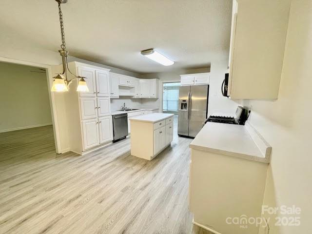205 Hidden Spring Dr, Salisbury, NC 28147 - kitchen featuring appliances with stainless steel finishes, a kitchen island, light wood-style flooring, light countertops, and white cabinets
