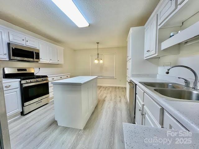 205 Hidden Spring Dr, Salisbury, NC 28147 - kitchen featuring appliances with stainless steel finishes, white cabinets, light wood-style floors, light countertops, and decorative light fixtures