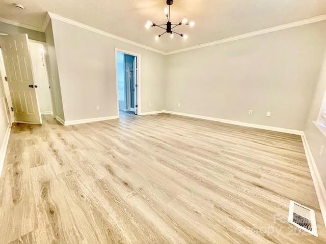 205 Hidden Spring Dr, Salisbury, NC 28147 - spare room with light wood-style flooring, ornamental molding, a chandelier, and a smoke detector