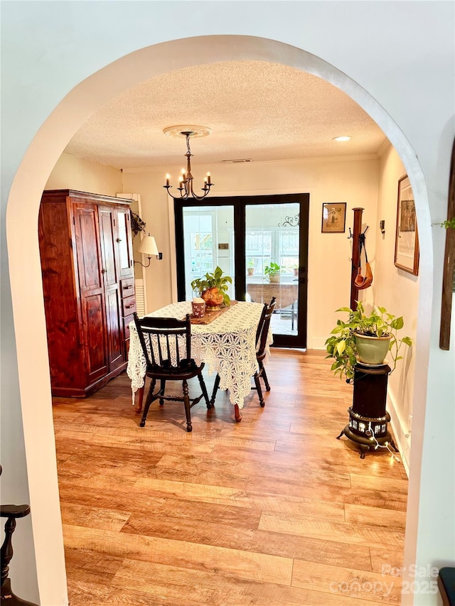 227 Reep Dr, Morganton, NC 28655 - dining room featuring arched walkways, light wood-style floors, a chandelier, and a textured ceiling
