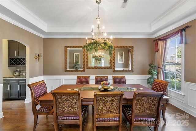 1204 Vaugelas Ct, Monroe, NC 28110 - dining room featuring a chandelier, wood finished floors, a decorative wall, a tray ceiling, and a wainscoted wall