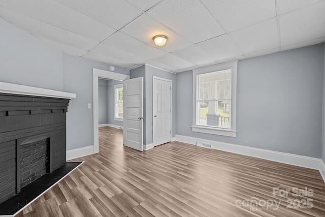 200 N Martin Luther King Jr Ave, Salisbury, NC 28144 - unfurnished living room with a drop ceiling, wood finished floors, healthy amount of natural light, and a brick fireplace