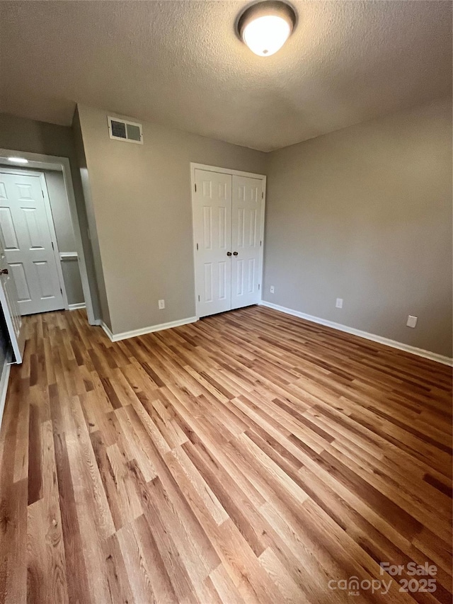 140 Lake Concord Rd NE Unit B7, Concord, NC 28025 - unfurnished bedroom with wood finished floors, a textured ceiling, and a closet