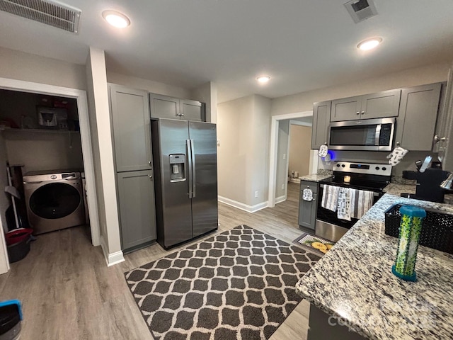 408 E 22nd St, Kannapolis, NC 28083 - kitchen with appliances with stainless steel finishes, washer / dryer, gray cabinets, and light wood-type flooring