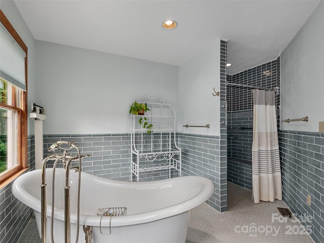 599 Red Fox Ln, Flat Rock, NC 28731 - bathroom featuring tile walls, tile patterned floors, healthy amount of natural light, a wainscoted wall, and tiled shower