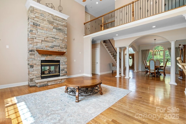 2301 Willow Creek Dr, Newton, NC 28658 - living room featuring decorative columns, arched walkways, crown molding, wood finished floors, and a stone fireplace