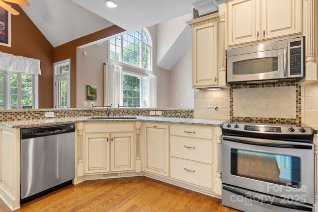 2301 Willow Creek Dr, Newton, NC 28658 - kitchen featuring stainless steel appliances, cream cabinetry, light wood finished floors, healthy amount of natural light, and high vaulted ceiling