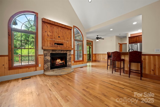 60 Bridge Ln, Tryon, NC 28782 - living room with wainscoting, light wood finished floors, a stone fireplace, wood walls, and lofted ceiling