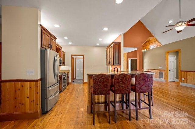 60 Bridge Ln, Tryon, NC 28782 - kitchen featuring appliances with stainless steel finishes, a kitchen bar, wainscoting, light wood-style flooring, and a peninsula