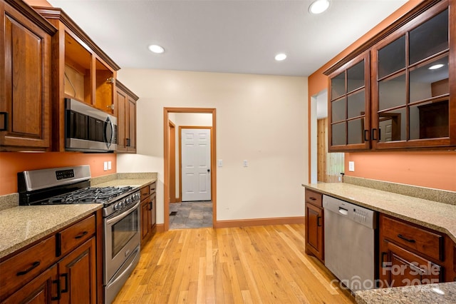 60 Bridge Ln, Tryon, NC 28782 - kitchen with appliances with stainless steel finishes, light wood-style flooring, light stone counters, glass insert cabinets, and recessed lighting