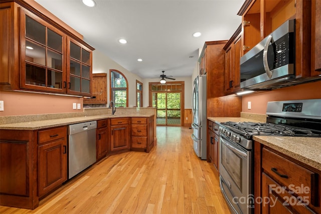 60 Bridge Ln, Tryon, NC 28782 - kitchen with appliances with stainless steel finishes, light wood finished floors, brown cabinets, a peninsula, and light stone countertops