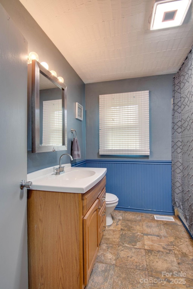 1715 Nelson Dr, Newton, NC 28658 - bathroom featuring vanity, a wainscoted wall, and stone finish floors