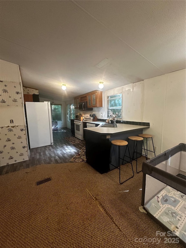 584 Ebenezer Rd, Old Fort, NC 28762 - kitchen featuring white appliances, a peninsula, dark wood-style floors, a breakfast bar, and glass insert cabinets