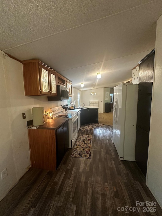 584 Ebenezer Rd, Old Fort, NC 28762 - kitchen with white appliances, dark wood-style floors, a peninsula, a textured ceiling, and brown cabinets