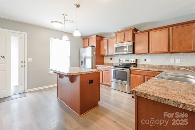8225 Midas Ln, Locust, NC 28097 - kitchen featuring appliances with stainless steel finishes, light wood-style flooring, decorative backsplash, and a kitchen island