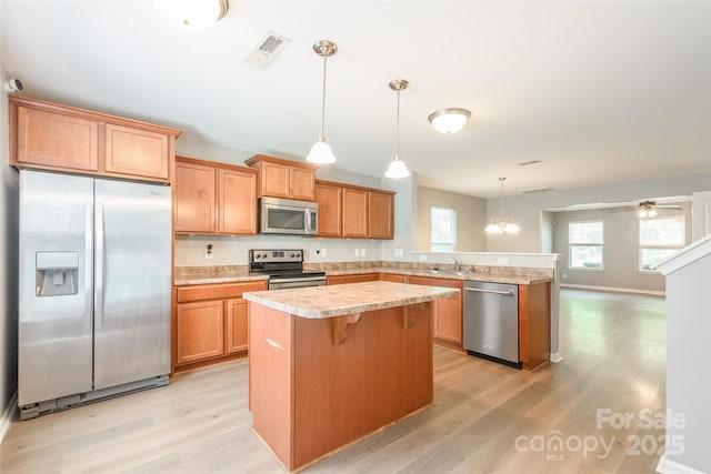 8225 Midas Ln, Locust, NC 28097 - kitchen featuring stainless steel appliances, a peninsula, light wood-style floors, light countertops, and a kitchen island