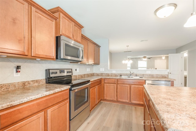 8225 Midas Ln, Locust, NC 28097 - kitchen featuring stainless steel appliances, light wood finished floors, light countertops, tasteful backsplash, and decorative light fixtures