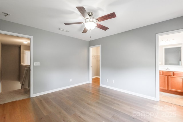 8225 Midas Ln, Locust, NC 28097 - unfurnished bedroom featuring light wood-style flooring, a spacious closet, ensuite bathroom, and a ceiling fan