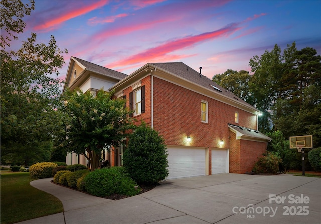 3015 Stanbury Dr, Matthews, NC 28104 - property exterior at dusk featuring an attached garage, concrete driveway, and brick siding