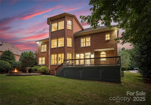 3015 Stanbury Dr, Matthews, NC 28104 - rear view of house with an outdoor fire pit, a deck, brick siding, and a lawn
