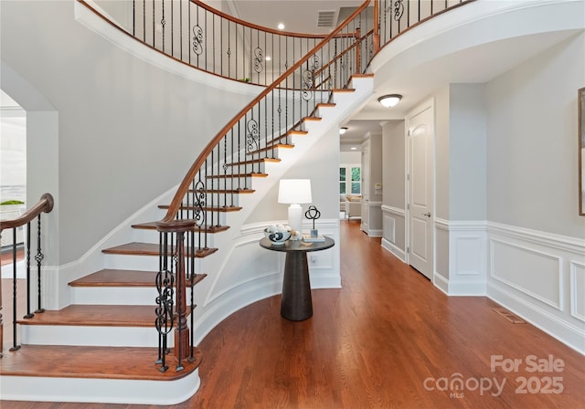 3015 Stanbury Dr, Matthews, NC 28104 - staircase with wood finished floors, a towering ceiling, a decorative wall, and a wainscoted wall