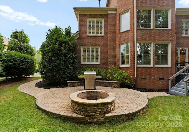 3015 Stanbury Dr, Matthews, NC 28104 - rear view of property featuring brick siding, a fire pit, a patio, a lawn, and crawl space
