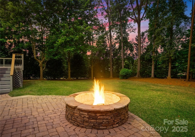 3015 Stanbury Dr, Matthews, NC 28104 - patio terrace at dusk featuring a fire pit, a lawn, a patio, stairs, and a wooden deck