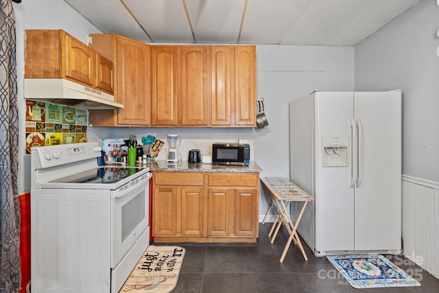74 Meadow Ave, Concord, NC 28025 - kitchen featuring white appliances, under cabinet range hood, a wainscoted wall, and dark tile patterned flooring