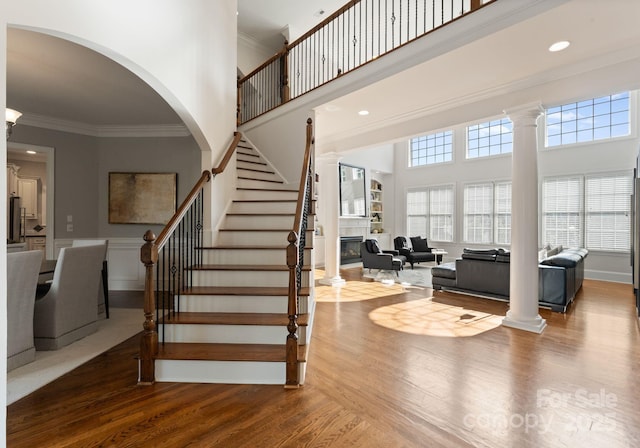 202 Montrose Dr, Waxhaw, NC 28173 - stairway featuring ornamental molding, wood finished floors, a towering ceiling, decorative columns, and arched walkways