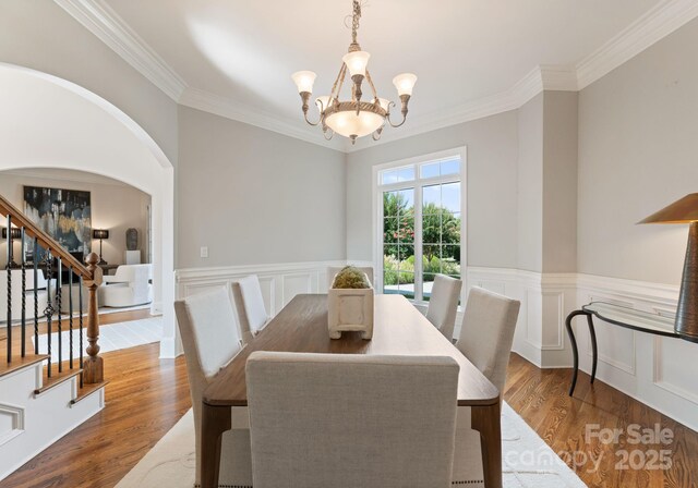 202 Montrose Dr, Waxhaw, NC 28173 - dining space featuring wood finished floors, ornamental molding, a chandelier, stairway, and arched walkways