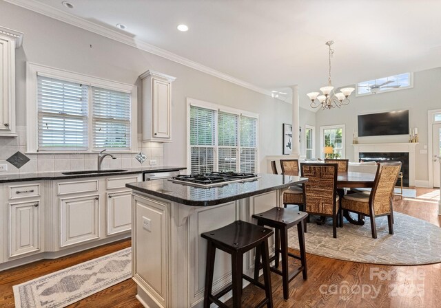 202 Montrose Dr, Waxhaw, NC 28173 - kitchen featuring a chandelier, stainless steel gas cooktop, wood finished floors, a kitchen breakfast bar, and backsplash