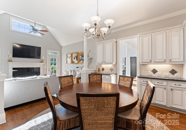 202 Montrose Dr, Waxhaw, NC 28173 - dining space featuring ceiling fan, dark wood-type flooring, a chandelier, a glass covered fireplace, and vaulted ceiling