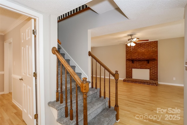 8749 Rittenhouse Cir, Charlotte, NC 28270 - stairs featuring wood finished floors, a ceiling fan, a fireplace, ornamental molding, and a textured ceiling
