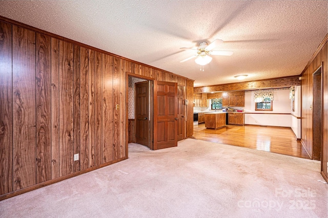 3781 Dover St, Claremont, NC 28610 - unfurnished living room with wood walls, a textured ceiling, ceiling fan, light carpet, and ornamental molding