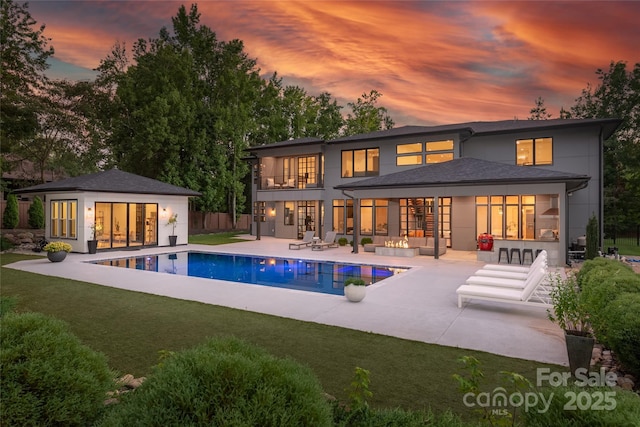 8403 Sarsfield Ct, Waxhaw, NC 28173 - back of house at dusk featuring a patio area, a storage structure, an outbuilding, a balcony, and an outdoor pool