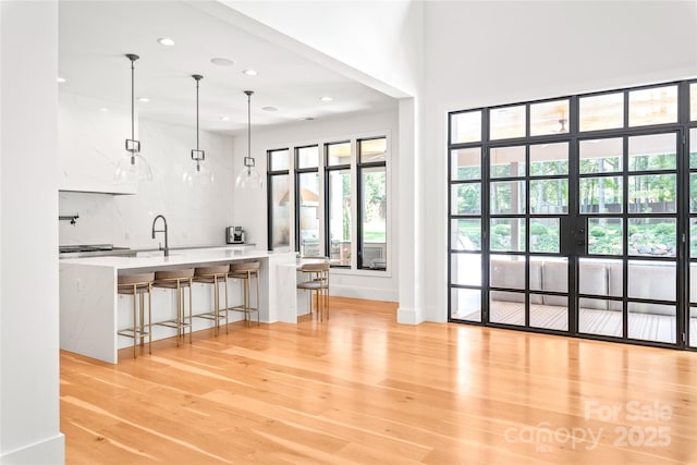 8403 Sarsfield Ct, Waxhaw, NC 28173 - kitchen with light wood-style flooring, recessed lighting, decorative backsplash, pendant lighting, and light countertops