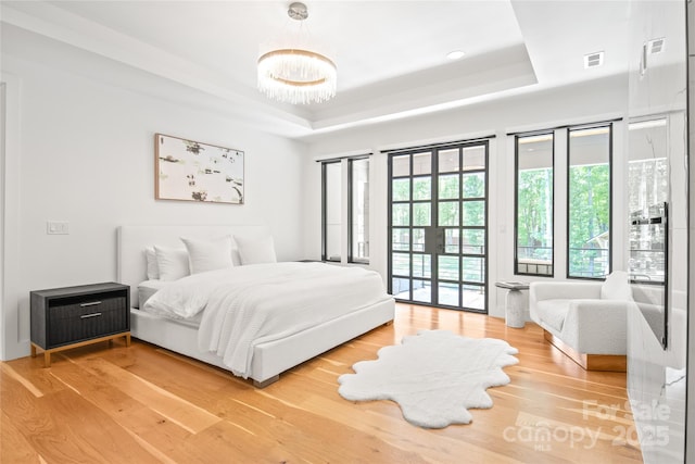 8403 Sarsfield Ct, Waxhaw, NC 28173 - bedroom featuring a raised ceiling, access to exterior, wood finished floors, a chandelier, and french doors